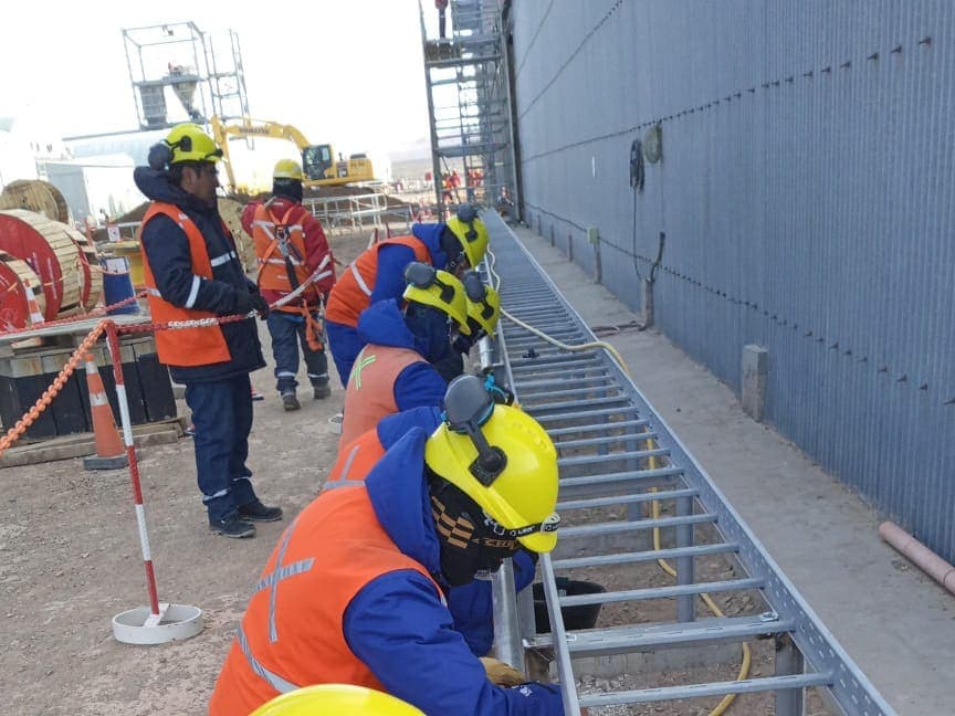 Cuadrilla colocando bandejas portacables a lo largo de un muro industrial
