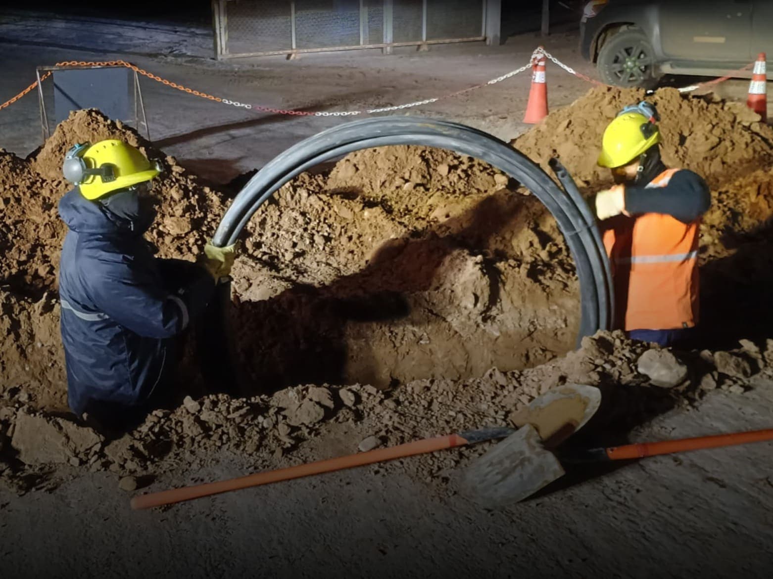 Dos operarios instalando cable en una zanja durante la noche