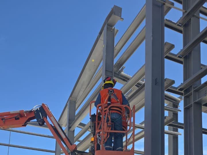 Operario en plataforma elevadora frente a una estructura metálica